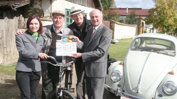 Schauspieler posieren mit einer Filmklappe und einem VW Käfer für „Polt“.