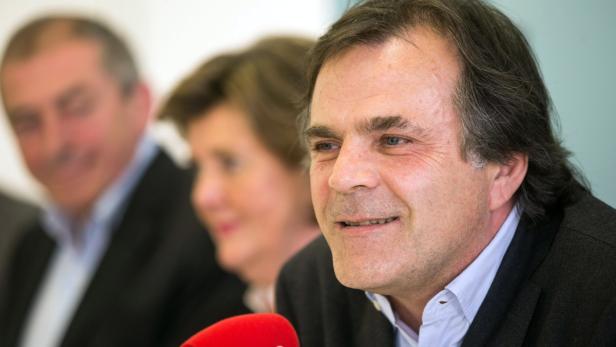 Ein Mann spricht während einer Pressekonferenz in ein rotes Mikrofon.