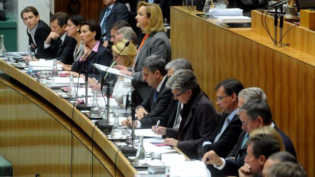 Eine Sitzung mit mehreren Personen in einem holzvertäfelten Raum.