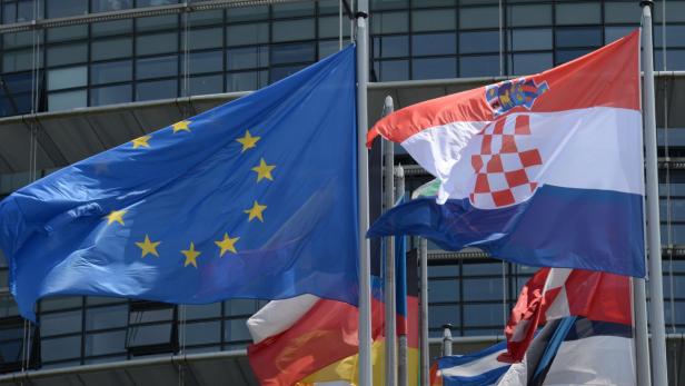 Die Europaflagge und die kroatische Flagge wehen vor einem modernen Gebäude.