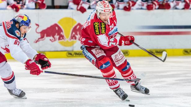 Zwei Eishockeyspieler in roter und weißer Spielkleidung kämpfen um den Puck.