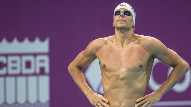 Ein Schwimmer mit Badekappe und Schwimmbrille steht mit verschränkten Armen da.