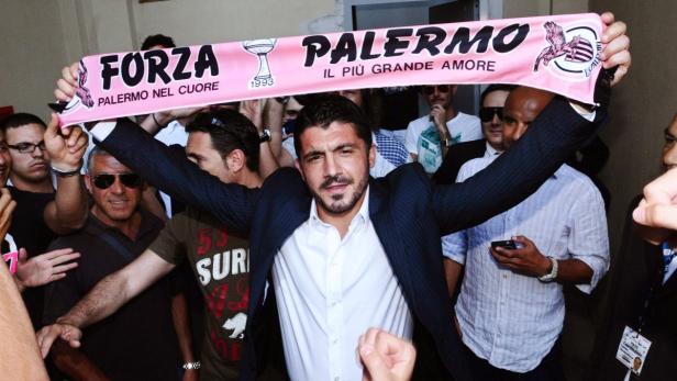 Ein Mann hält einen Schal mit der Aufschrift „Forza Palermo“ in die Höhe.