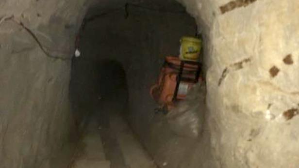 Ein Tunnel mit Werkzeugen und einem Eimer an der Seite führt in die Dunkelheit.