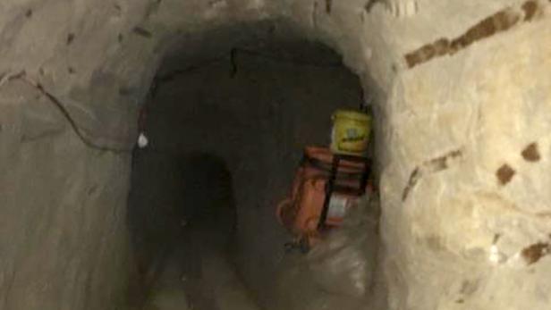 Ein Tunnel mit einer Kettensäge und einem gelben Eimer darin.
