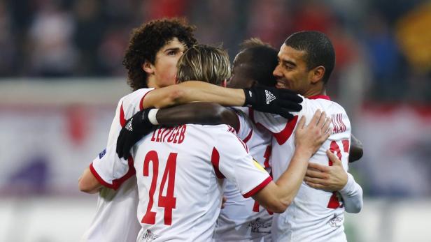 Mehrere Fußballspieler umarmen sich in ihren Trikots von RB Leipzig.
