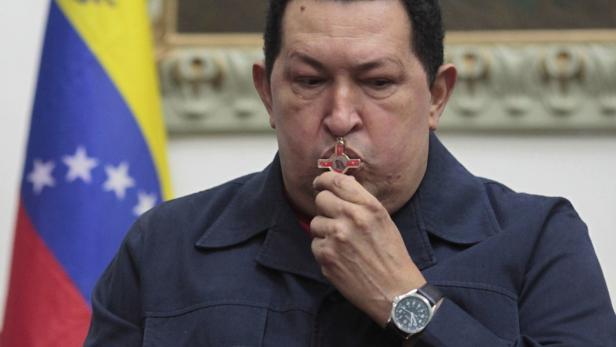 Venezuelan President Hugo Chavez kisses a crucifix as he speaks during a national broadcast at Miraflores Palace in Caracas December 9, 2012. Chavez said on Saturday he would undergo another cancer operation in the coming days after doctors in Cuba found a third recurrence of malignant cells in his pelvic area. The news is a big blow for his supporters in South America&#039;s biggest oil exporter, who elected him in October to a new six-year term in power. Chavez has twice said he was cured, and then had to return to Cuba for more surgery. In a televised broadcast flanked by ministers at the Miraflores presidential palace, Chavez said that if anything happened to him and a new vote had to be held, his supporters should vote for Vice President Nicolas Maduro - the first time the socialist leader has named a successor. REUTERS/Miraflores Palace/Handout (VENEZUELA - Tags: POLITICS)