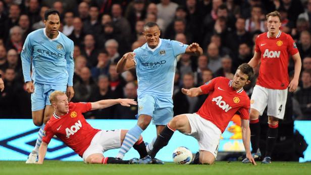 epa03201821 Manchester City&#039;s Vincent Kompany (C) vies for the ball with Manchester United&#039;s Paul Scholes (L) and Michael Carrick (R) during the English Premier League soccer match at the Etihad Stadium, Manchester, Britain, 30 April 2012. EPA/PETER POWELL DataCo terms and conditions apply. http//www.epa.eu/downloads/DataCo-TCs.pdf