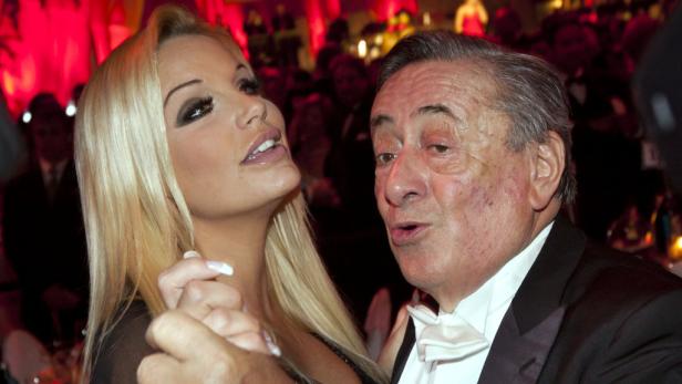 Eine blonde Frau tanzt mit einem älteren Mann im Anzug.