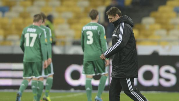 Ein Trainer geht an einer Gruppe von Fußballspielern vorbei.