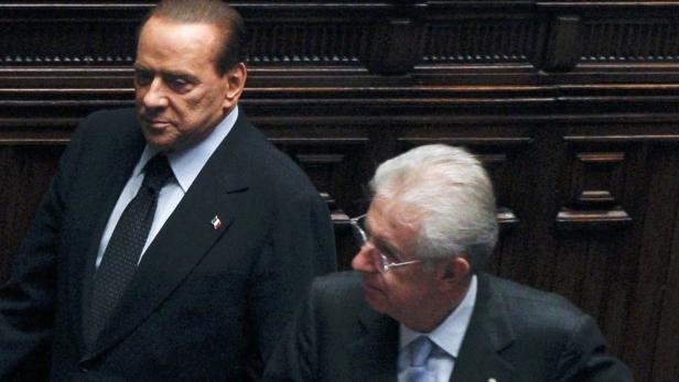 Italian Prime Minister Mario Monti (R) looks on as his predecessor Silvio Berlusconi walks beside him during a vote of confidence at the Lower House of Parliament in Rome November 18, 2011. REUTERS/Tony Gentile (ITALY - Tags: POLITICS)