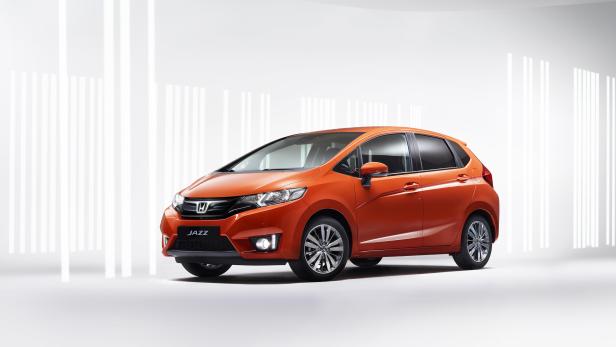 Ein orangefarbener Honda Jazz vor einem weißen Hintergrund mit Lichteffekten.