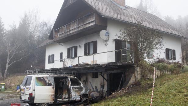 Ein ausgebrannter Lieferwagen vor einem Wohnhaus mit Brandschäden.