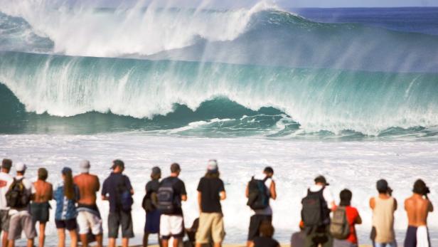 Spectators watch a massive wave hit the surf at the Banzai pipeline on the north shore of Oahu, Hawaii, December 13, 2004. The Rip Curl Pro Pipeline Masters contest, due to be held in Oahu, was placed on hold due to stormy surf conditions rocking the north shore earlier. The Rip Curl Pipeline Masters is the final event on the 2004 Fosters ASP World Championship Tour and features the top 45 surfers and three wild card entrants. FOR EDITORIAL USE ONLY REUTERS/ASP/Pierre Tostee/Handout