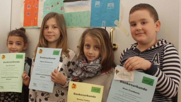 Vier Kinder präsentieren stolz ihre Dankesurkunden vor einem Wandbild mit bunten Häusern.
