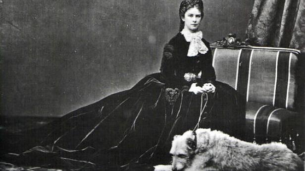 Kaiserin Elisabeth von Österreich sitzt mit ihrem Hund auf einem Stuhl.