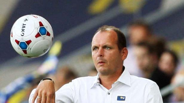 Ein Mann in einem weißen Hemd mit einem Fußball der Marke Jako.