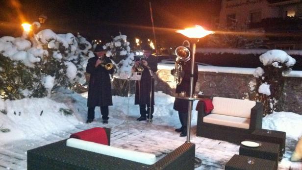 Drei Musiker spielen im Schnee auf Trompeten und einer Tuba.