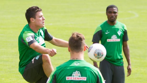 Drei Fußballspieler von Werder Bremen trainieren auf dem Rasen.
