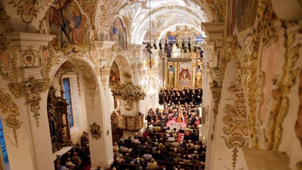 Ein Konzert mit Orchester und Chor in einer reich verzierten Kirche mit Publikum.
