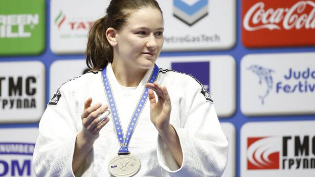 Eine Judo-Kämpferin mit einer Medaille um den Hals klatscht Beifall.
