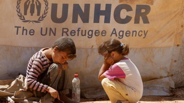 Zwei Kinder sitzen vor einem Zelt des UNHCR.