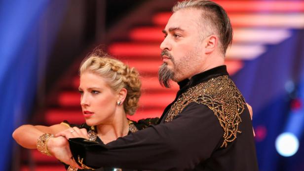 Ein Tanzpaar in aufwändiger Kleidung auf einer Bühne.