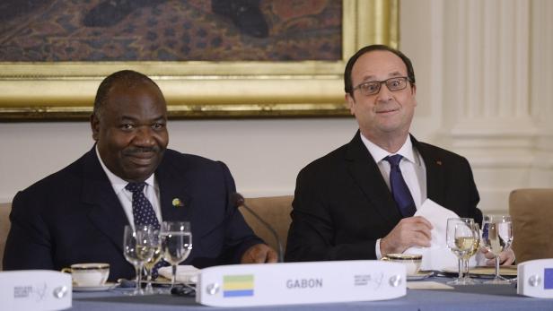 Ali Bongo Ondimba und François Hollande sitzen an einem Tisch mit der Aufschrift „Gabun“.