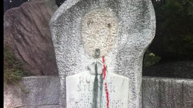 Eine beschmierte Steinskulptur mit einer angedeuteten menschlichen Figur.