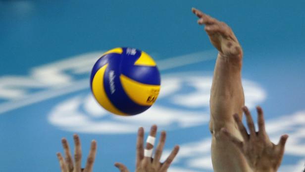 Ein Volleyballspieler schlägt einen gelb-blauen Ball.