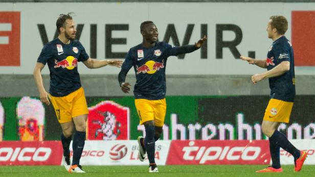 Drei Fußballspieler von RB Salzburg feiern auf dem Spielfeld.