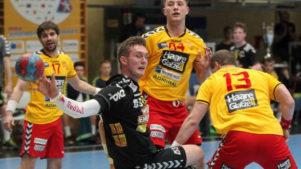 Ein Handballspieler im schwarzen Trikot beim Wurf auf das Tor.