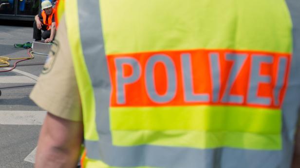 Ein Polizist mit Warnweste steht auf der Straße, im Hintergrund ein weiterer Polizist.