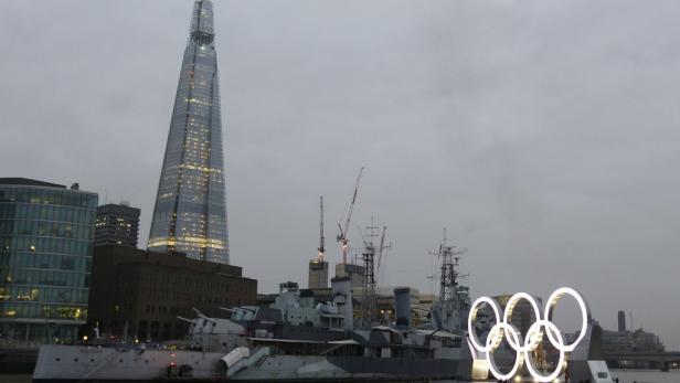 dapdA tug boat pulls a barge with giant Olympic rings that are 11 meters (36 feet) tall and 25 meters (82 feet) wide, as they are unveiled on the River Thames in London, as preparations for the upcoming London 2012 Olympic games gather pace in London earl Die HMS Belfast und die leuchtenden olympischen Ringe vor der Skyline von London.