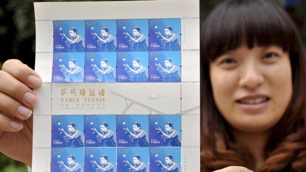 Eine Frau hält einen Bogen chinesischer Briefmarken zum Thema Tischtennis in der Hand.