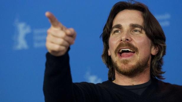 Christian Bale gestikuliert vor einem blauen Hintergrund.