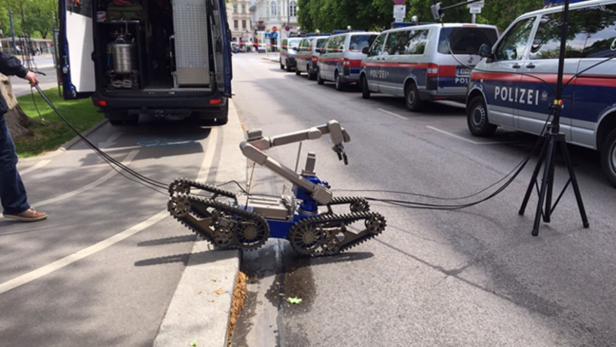 Ein Entschärfungsroboter der Polizei steht auf einer Straße in der Nähe von Einsatzfahrzeugen.