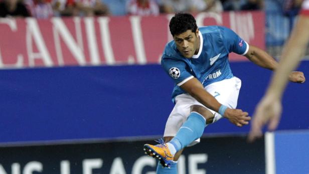 Ein Fußballspieler in blauem Trikot schießt den Ball.