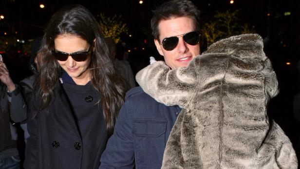 Tom Cruise und Katie Holmes mit Kind in Pelzjacke bei einer Veranstaltung.