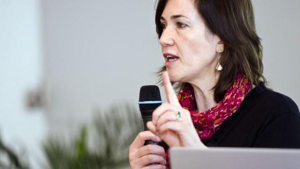 Eine Frau spricht in ein Mikrofon und gestikuliert mit dem Finger.