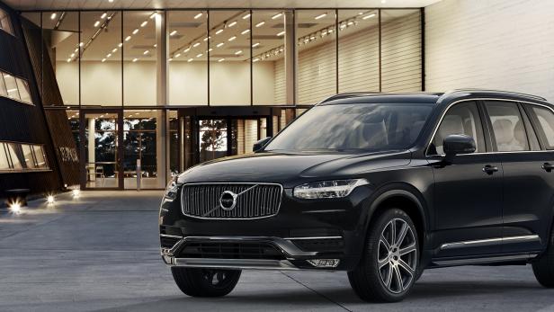 Ein schwarzer Volvo XC90 steht vor einem modernen Gebäude.