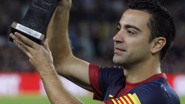 Xavi Hernández hält eine Trophäe in die Höhe.