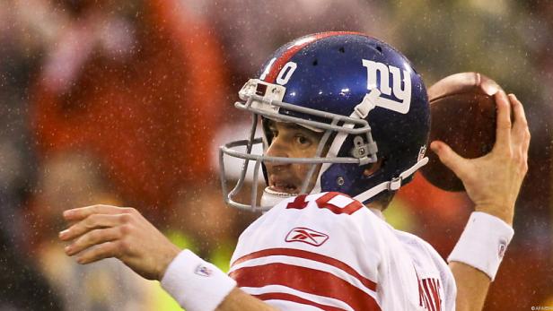 Ein Quarterback der New York Giants wirft im Regen einen Football.