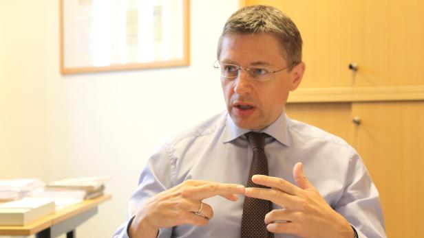 Ein Mann mit Brille und Krawatte gestikuliert während eines Gesprächs.