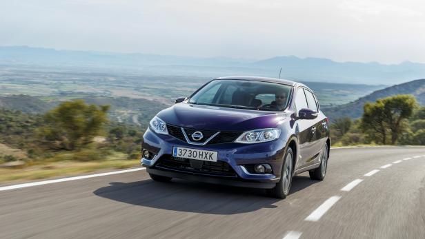Ein violetter Nissan Pulsar fährt auf einer kurvenreichen Straße in hügeligem Gelände.