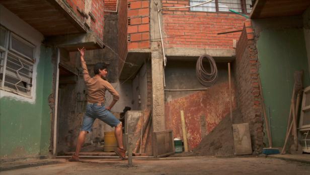 Ein Mann posiert in einem Hinterhof mit unfertigen Ziegelbauten.