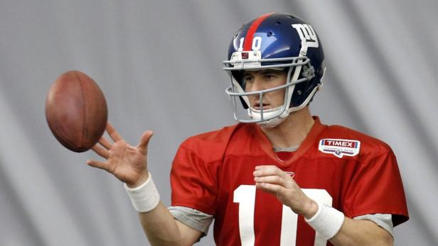 Ein Footballspieler der New York Giants mit Helm und Trikot wirft einen Football.