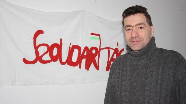 Ein Mann steht vor einem Banner mit der Aufschrift „Solidarietà“.
