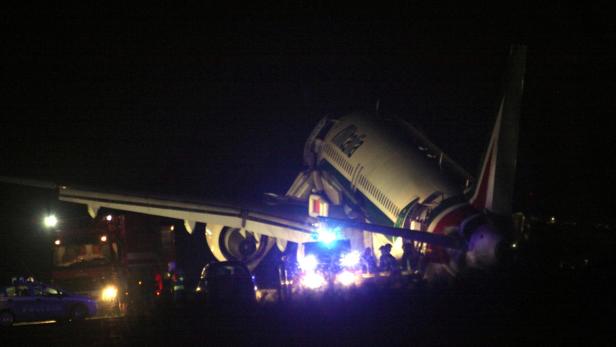 Ein beschädigtes Flugzeug der Alitalia wird nachts von Rettungskräften untersucht.