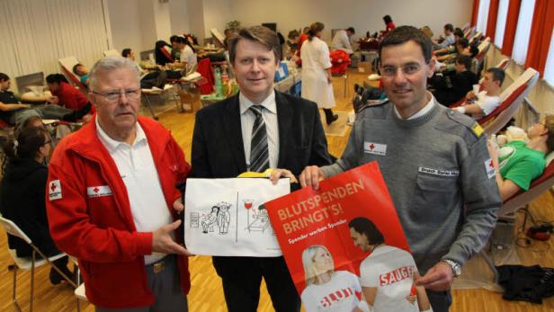 Drei Personen werben für eine Blutspendeaktion des Deutschen Roten Kreuzes.